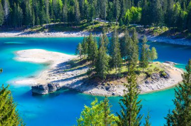 Small island in the middle of Cauma Lake (Caumasee) with crystal blue water in beautiful mountain landscape scenery at Flims, Graubuenden - Switzerland