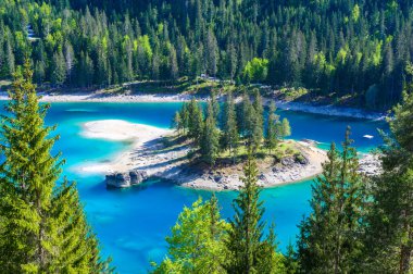 Small island in the middle of Cauma Lake (Caumasee) with crystal blue water in beautiful mountain landscape scenery at Flims, Graubuenden - Switzerland