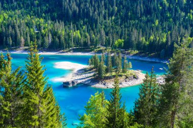 Small island in the middle of Cauma Lake (Caumasee) with crystal blue water in beautiful mountain landscape scenery at Flims, Graubuenden - Switzerland