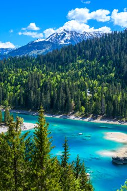 Small island in the middle of Cauma Lake (Caumasee) with crystal blue water in beautiful mountain landscape scenery at Flims, Graubuenden - Switzerland