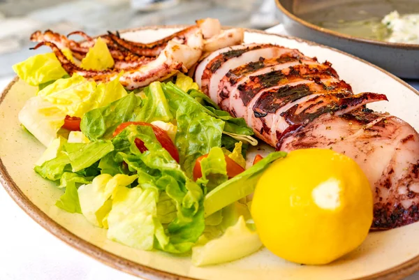 在希腊雅典的一家餐馆里 大烤鱿鱼和半只柠檬 罗曼式和番茄沙拉一起享用 — 图库照片