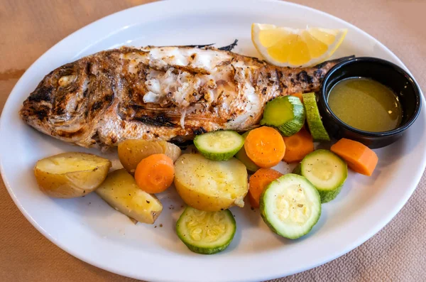 在希腊的一家餐馆里 有新鲜蔬菜和小土豆的烤全红色小吃 免版税图库照片