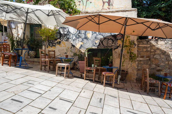 Athens, Greece - May 26, 2023: Tables, Chairs and Sun Umbrellas from a Restaurant Are Placed on the Street with a Steep Incline in the Plaka Area 