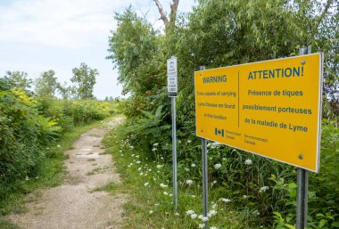 Çevre Kanada 'dan iki dilli bir işaret. Chatham Ontario' daki St. Clair Ulusal Vahşi Yaşam Bölgesi 'nde Lyme Hastalığı taşıyan keneler hakkında insanları uyardı.