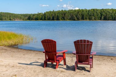Wolseley Körfezi kıyısında, Fransız Nehri İl Parkı 'nda İki Kırmızı Adirondack Sandalyesi