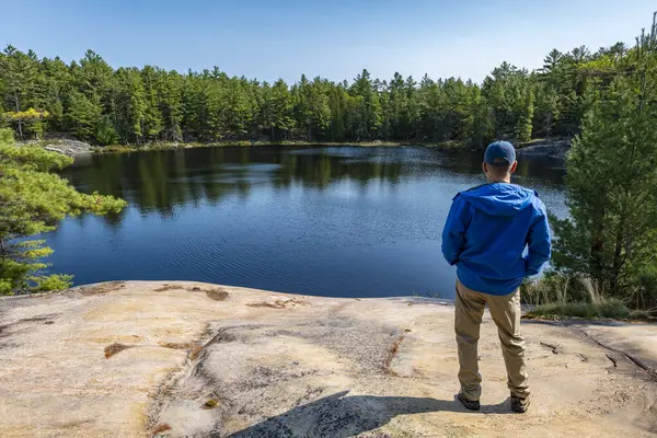 stock image A Man Standing by the Edge of a Big Rock Looking at Moira Pond, French River Provincial Park