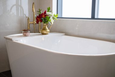 Pirinçten bir muslukla süslenmiş beyaz bir porselen küvet.