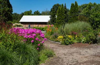 Güzel manikürlü bahçe Beyaz çatılı eski ahşap ahırı çerçeveliyor