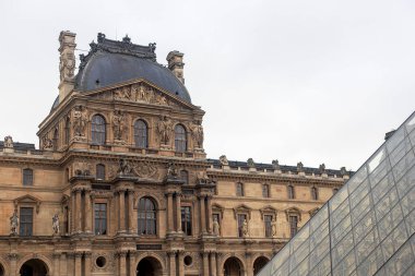 Paris 'teki Louvre Müzesi' nin Pavillon Denon binasının ön cephesinin ve öndeki piramidin fotoğrafı.