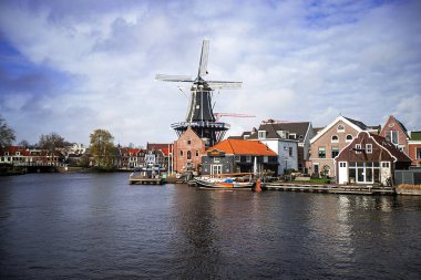 Harleem, Hollanda 'da bir yel değirmeninin fotoğrafı ve şehrin kanalı ve mimarisi.