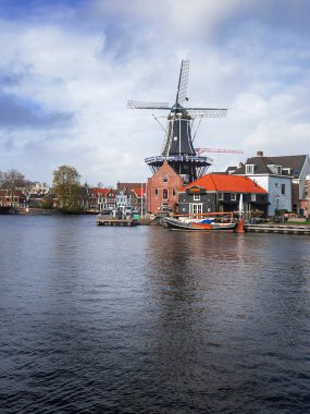 Harleem, Hollanda 'da bir yel değirmeninin fotoğrafı ve şehrin kanalı ve mimarisi.