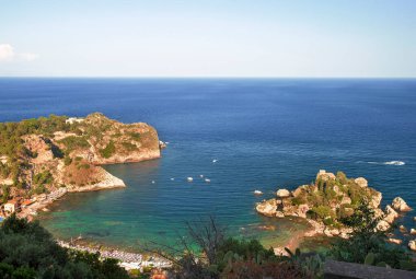 Photograph of the beautiful Isola Bella in the coast of Taormina in Sicily. Photo taken during the summer afternoon, houses and trees, boats and the Mediterranean se