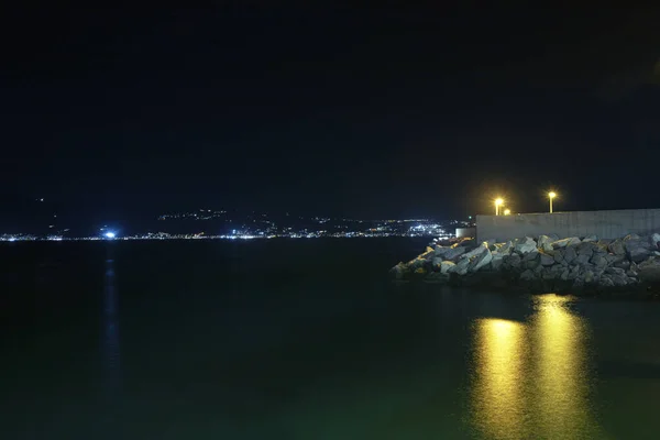 Photograph of the coast of Villa San Giovanni, in Reggio Calabria, at night and the island of Sicily. Long exposure photography, silk effect in sea water