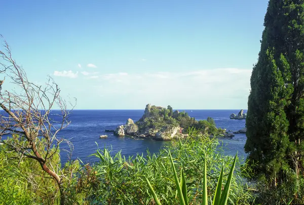 Photograph of the beautiful Isola Bella in the coast of Taormina in Sicily. Photo taken during the summer afternoon, houses and trees, boats and the Mediterranean se