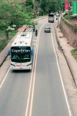San Gil, Santander, Colombia, April 26, 2024, landscape of Santander Avenue in San Gil with moderate traffic, and a bus from the transportation company Copetran in the foreground clipart