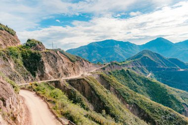 Güneşli bir günde mavi gökyüzüyle asfaltsız bir yolu olan Kolombiya 'nın dağlık manzarası