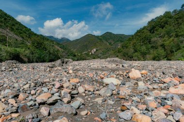 Bir çığ sonucu oluşan taşlardan oluşan bir nehirle dağlık bir arazi ve nehri kuruyan güçlü bir yaz.
