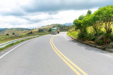 Ufukta kaybolan bir yolu olan dağ manzarası ve soğuk bir günde yol alan bir kargo kamyonu.