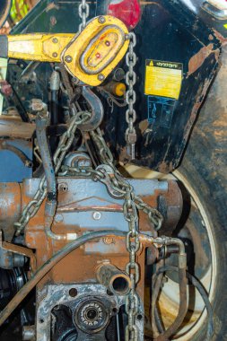 Bir çiftlikteki doğaçlama bir atölyede bir traktör motorunu makara ve zincirle sökmek