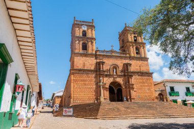 Barichara, Santander, Kolombiya, 11 Ekim 2024. Ana meydandan Barichara Katedrali 'nin manzarası. Bu tarihi bina taş ve kerpiç tekniklerinden yapılmıştır. Birçok turist güneşli günün ve mimarinin tadını çıkarırken görülebilir.