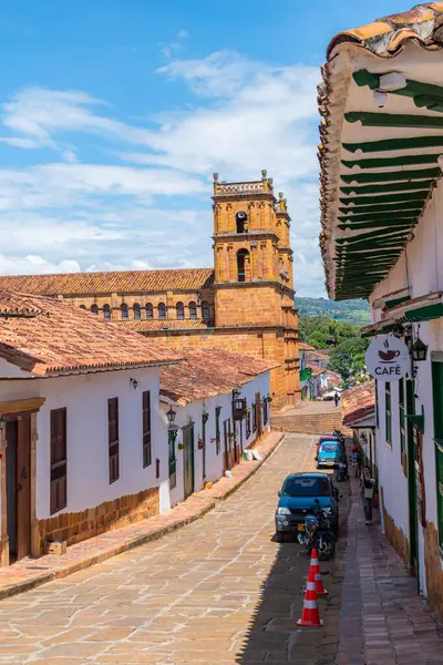 Barichara, Santander, Kolombiya, 11 Ekim 2024. Koloni mimarisi tarafından açık mavi gökyüzü altında çerçevelenmiş, ana katedrale doğru uzanan huzurlu bir kaldırım taşı sokağının dikey görüntüsü..