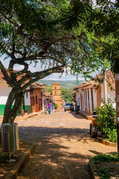 Barichara, Santander, Kolombiya, 11 Ekim 2024. Mezarlık parkından çekilen Barichara 'nın barışçıl bir görüntüsü. Katedral arka planda görünüyor. Aşağıdaki kaldırım taşı caddesinde birkaç yayanın sessiz koloni boyunca yürüdüğünü görüyoruz.