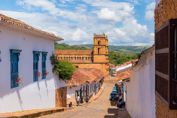 Barichara, Santander, Kolombiya, 11 Ekim 2024. Arka planda ikonik katedralin yükseldiği açık bir günde Barichara kentsel manzarası. Çamur kil kiremit çatılı renkli evler, süslenip püslenmiş bahçelerle bezenmiştir.,
