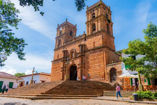 Barichara, Santander, Kolombiya, 11 Ekim 2024. Barichara 'nın heybetli taş katedrali sabah güneşinin altında sıcak tonlarını ve sömürge mimarisini gözler önüne seriyor. Birkaç kişi giriş merdivenlerinde toplanıp, hayat katıyor.