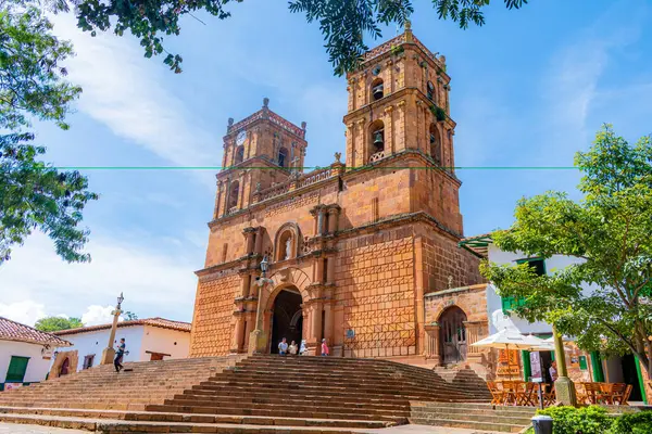 Barichara, Santander, Kolombiya, 11 Ekim 2024. Barichara 'nın taş katedrali bulutsuz mavi gökyüzünün altında görkemli bir şekilde duruyor. Sömürge tarzında inşa edilmiş koyu renkli cephesi güneş ışığında parlıyor, mimari güzelliği ve kültünü yansıtıyor.