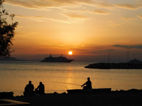 Glyfada, Atina, Yunanistan sahillerinde altın bir günbatımında balık tutmak