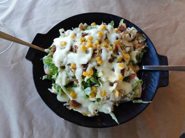 Domatesli tavuk salatası, marul, mısır ve sos, restoranda servis edilir.