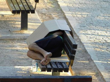 Parktaki bankta uyuyan evsiz bir adam