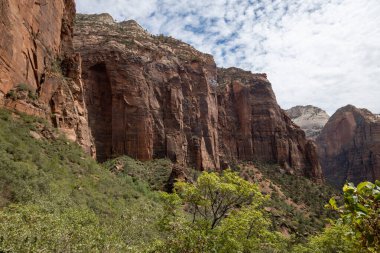 Kremadan, pembeden ve kırmızıdan oluşan devasa kumtaşı kayalıklarına bak. Parlak mavi gökyüzüne doğru süzülüyor. Dar bir kanyonda vahşi doğayı deneyin - burası Zion Ulusal Parkı, Utah, ABD turizm merkezleri