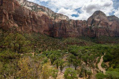 Kremadan, pembeden ve kırmızıdan oluşan devasa kumtaşı kayalıklarına bak. Parlak mavi gökyüzüne doğru süzülüyor. Dar bir kanyonda vahşi doğayı deneyin - burası Zion Ulusal Parkı, Utah, ABD turizm merkezleri