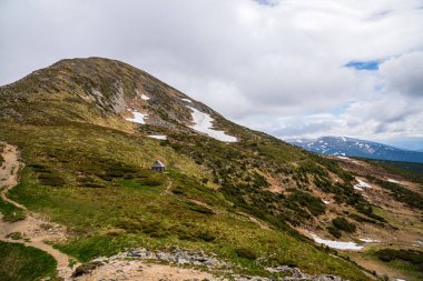 Ukrayna Karpatlarının gökyüzü ve bulutların arka planında asılı duran Hoverla Dağı manzarası.