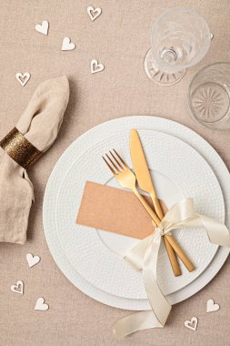 Festive wedding, birthday table setting with golden cutlery and porcelain plate. Blank place card mockup. Party menu template. Flat lay, top view