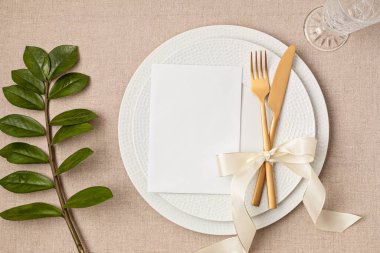 Festive wedding, birthday table setting with golden cutlery and porcelain plate. Blank card mockup. Party menu template. Flat lay, top view