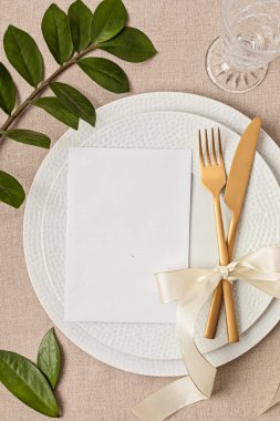 Festive wedding, birthday table setting with golden cutlery and porcelain plate. Blank card mockup. Party menu template. Flat lay, top view