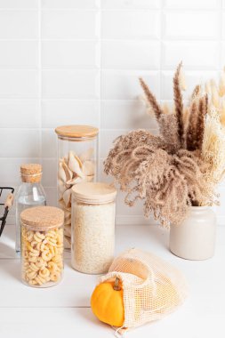 Tahıl çeşitleri, tahıl gevreği ve cam kavanozlarda makarna ve ahşap masada mutfak gereçleri. Sağlıklı dengeli gıda, etik sürdürülebilir yaşam tarzı, sıfır atık, çevre dostu konsept.