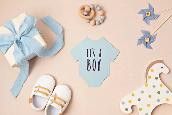 Baby shower, gender reveal party. It\'s a boy message over paper cut onesie. Flatlay, top view. Newborn gifts. Invitation,