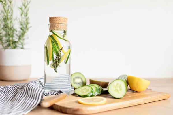 Infused  water with cucumber, lemon and thyme in glass bottle on wooden table. Diet, detox, healthy eating, weight loss concept