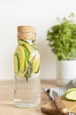 Tahta masadaki cam şişede salatalık, limon ve kekik ile doldurulmuş su. Diyet, detoks, sağlıklı beslenme, kilo verme konsepti