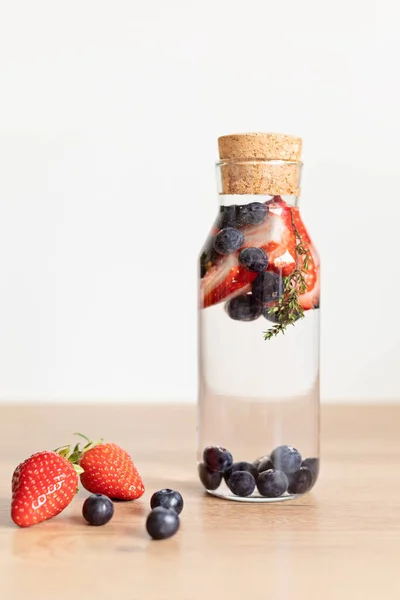 木製のテーブルの上にガラス瓶にイチゴとブルーベリーと水を注入しました ダイエット デトックス 健康的な食事 減量の概念 — ストック写真