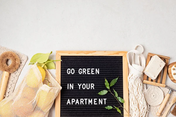 Zero waste home accessories and letter board with the text go green in your apartment. Sustainable, eco friendly lifestyle idea. Flat lay, top, view