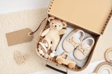 Cinsiyet ayrımı olmayan bebek kıyafetleri ve aksesuarlarıyla hediye sepeti. Yeni doğmuş organik ayakkabı, moda, markalaşma, küçük işletme fikri. Düz yatış, üst görünüm