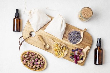 Pamuk torbalarda botanik karışımları, tuz, bitkiler, doğal yağlar. Doğal ilaç, bitkisel ilaç, banyo için karışımlar ve ahşap masa arkasında çay.
