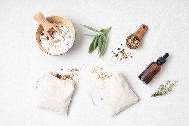 Pamuk torbalarda botanik karışımları, tuz, bitkiler, doğal yağlar. Doğal ilaç, bitkisel ilaç, banyo için karışımlar ve ahşap masa arkasında çay.