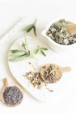 Botanik karışımlar, bitkiler, doğal yaşam için esanssal yağlar. Doğal ilaç, bitkisel ilaç, banyo için karışımlar ve beyaz tahta masa arkasında çay.