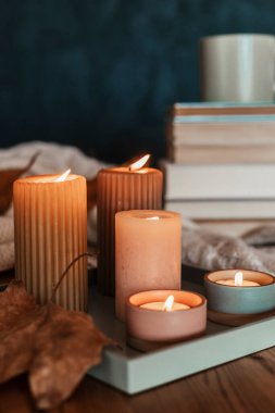 İçinde bir yığın kitap, kupada sıcak içecek ve sıcak battaniye olan kompozisyon. Soğuk hava ve bir fincan kahve için samimi bir okuma sahnesi.