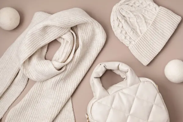 Beige quilted puffed bag and woolen accessories on pastel background. Stylish woman outerwear. Winter fashion accessories